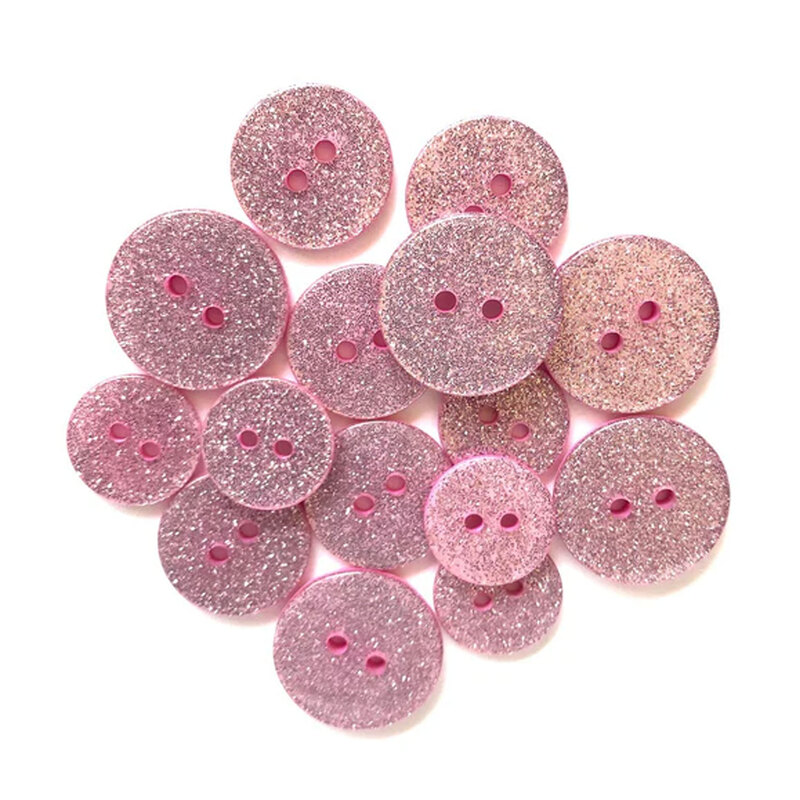 Pile of light pink glitter buttons against a white background