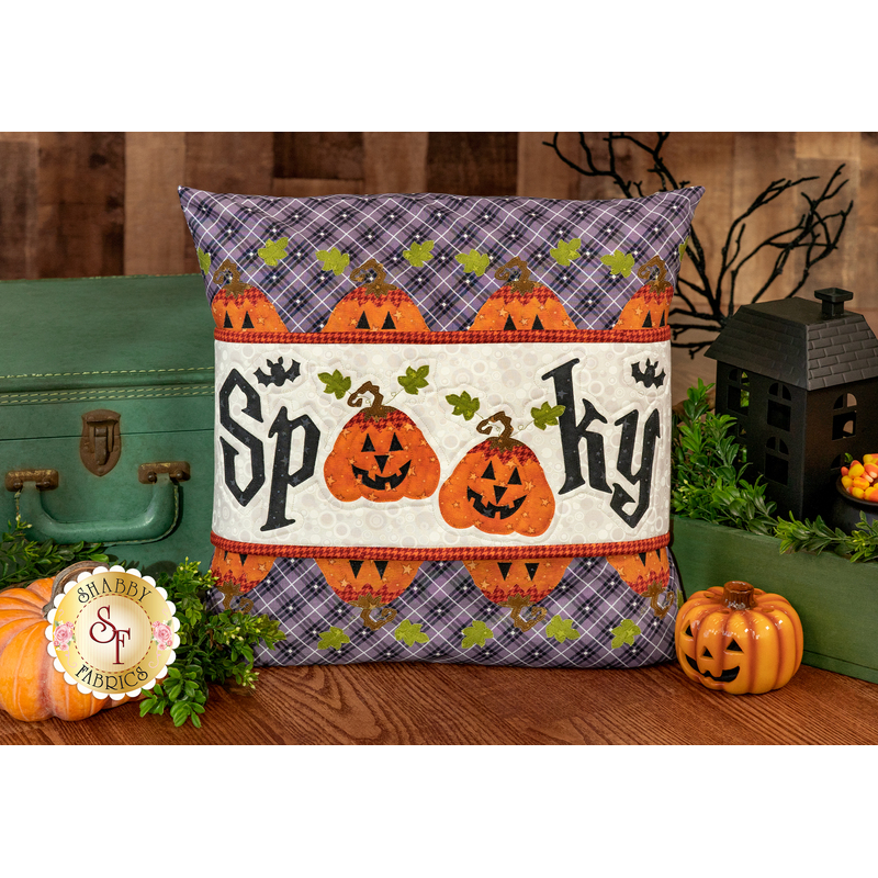 The completed Spooky Pillow Wrap & Cover, colored in purple, orange, cream, and green fabrics. The word 