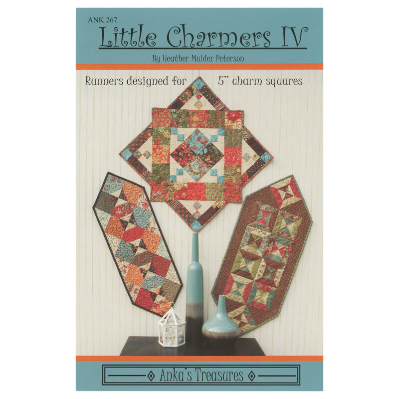 The front of the Little Charmers IV pattern showing the finished table runners and topper on a cream paneled background with coordinating colorful decor on a dark brown wooden table in front of the projects.