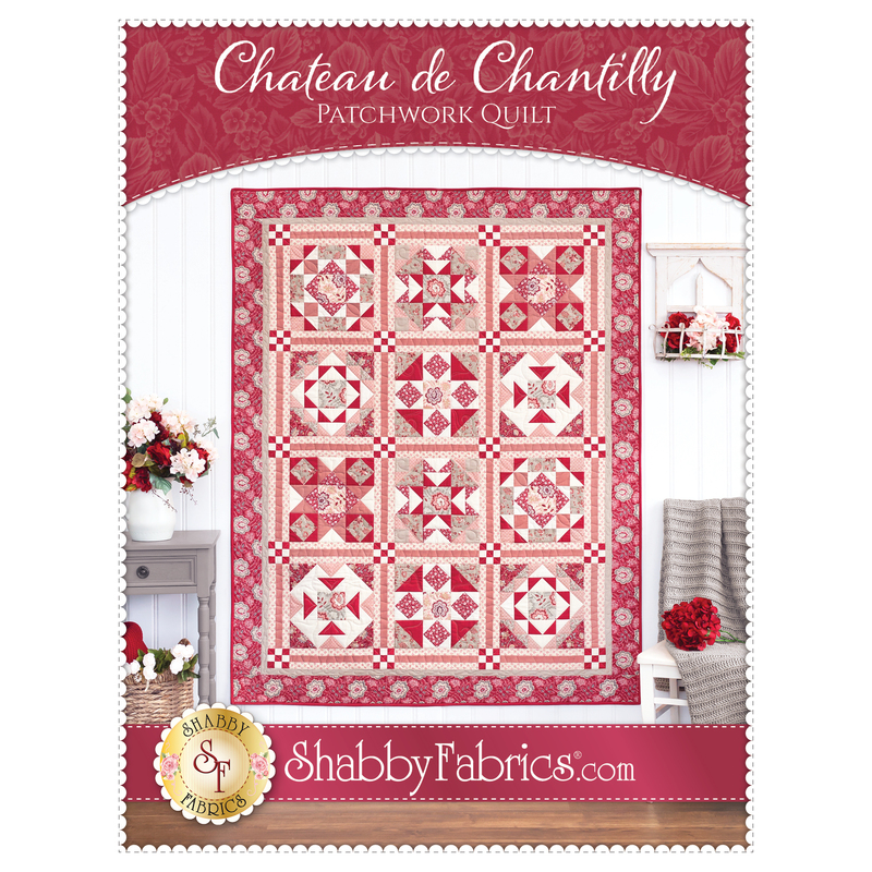 Front cover of the pattern showing the completed Chateau de Chantilly Patchwork Quilt in vibrant shades of red, pink, and white, hung on a white paneled wall and staged with coordinating furniture and decor.