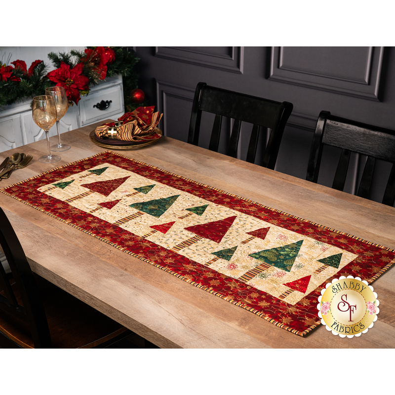 The completed Fa La La Forest Runner in cream, green, and red fabrics, staged on a wood table with coordinating plates and decor.