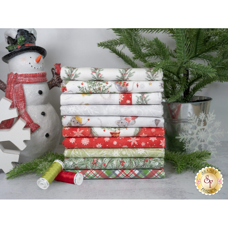 A stack of fabrics available in The Christmas Mouse Flannel fq set, with a tree and snowflakes and a snowman and thread.