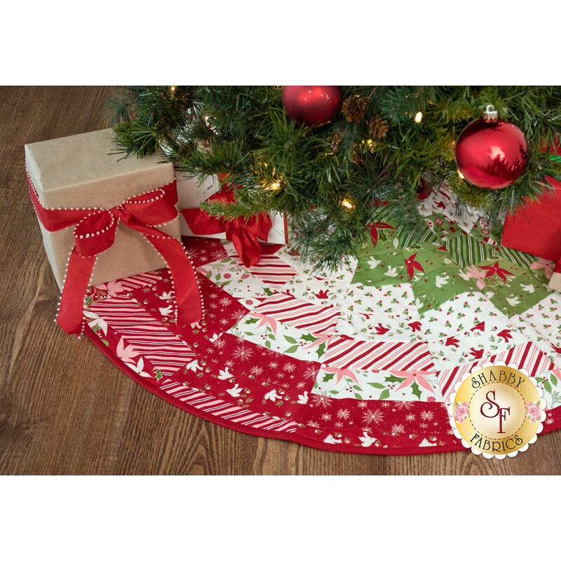 A shot of the completed Bargello tree skirt staged under a decorated Christmas tree and kraft paper wrapped presents.