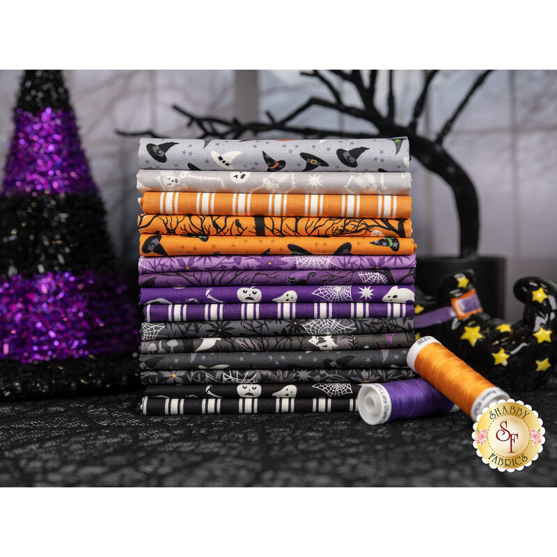 A stack of fabrics included in the Witchy Woods fabric collection. with a tree and a witch hat and a witch's shoe and thread.
