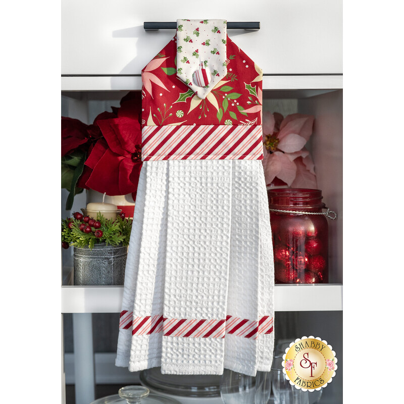 The completed hanging towel in red, hung from a kitchen drawer and staged with coordinating decor and flowers.