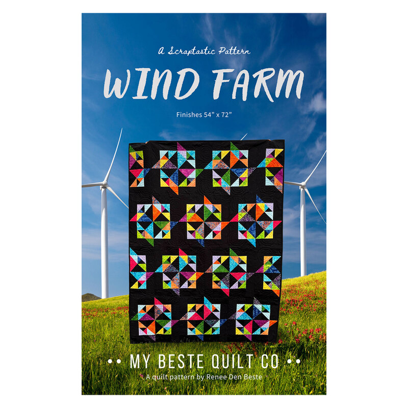 The front of the Wind Farm pattern featuring the finished quilt being held up in front of a wind farm on a grassy hill.