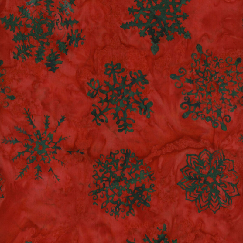 Red textile background featuring various intricate green snowflake patterns.