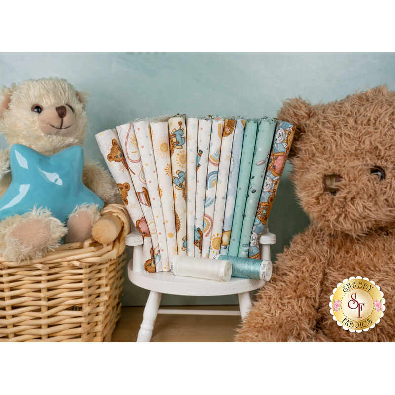 A stack of the fabrics featured in the Boho Buddies FQ set, with a chair and a basket and teddy bears and a star and thread.