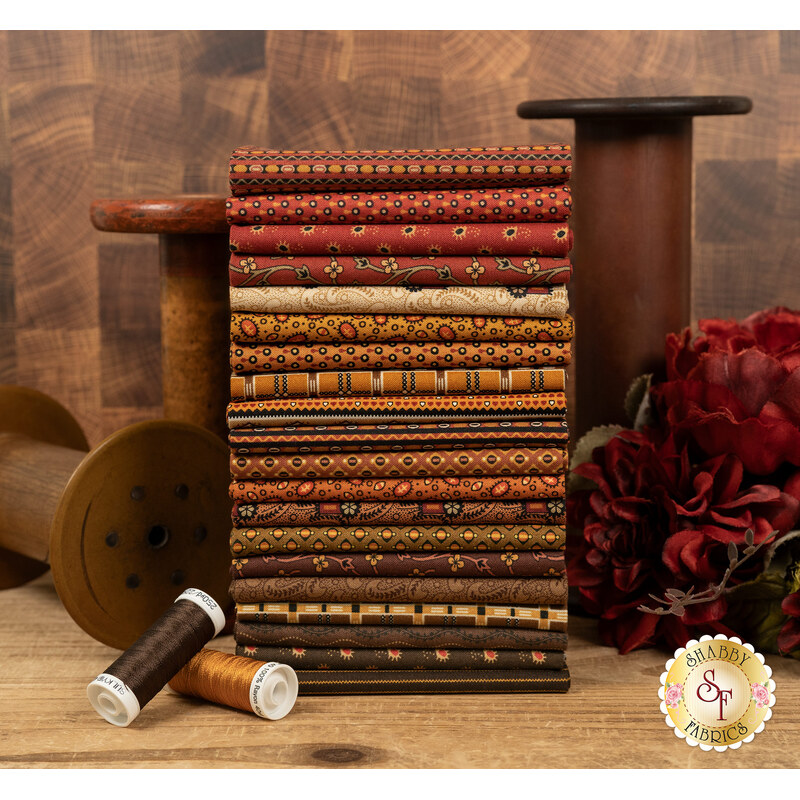 A stack of the fabrics included in the Spice Market FQ set, with flowers and spools and thread.