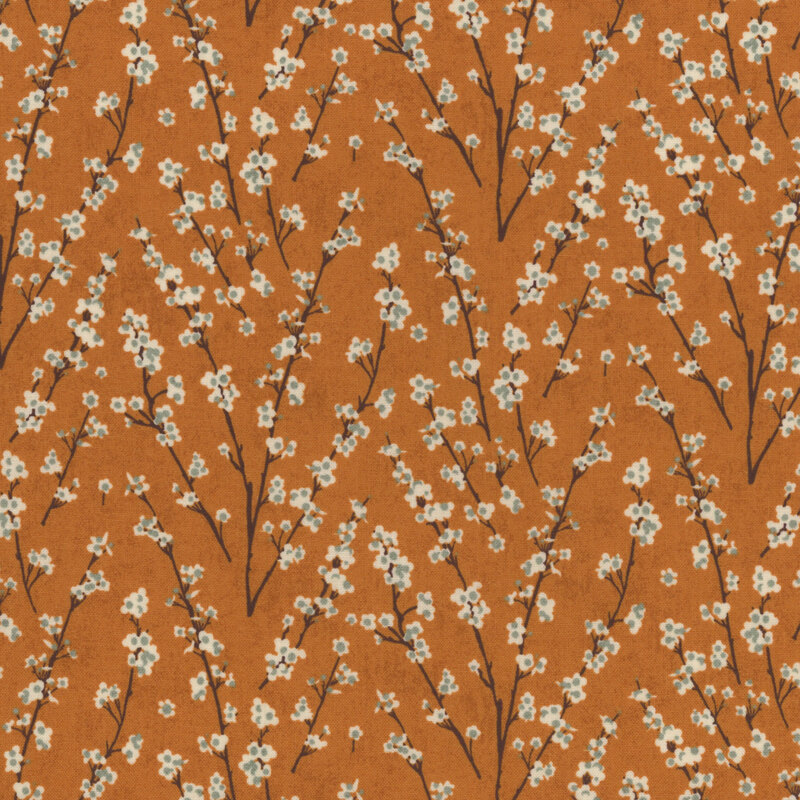 Orange fabric covered with delicate branches and cream flowers, creating a floral pattern.