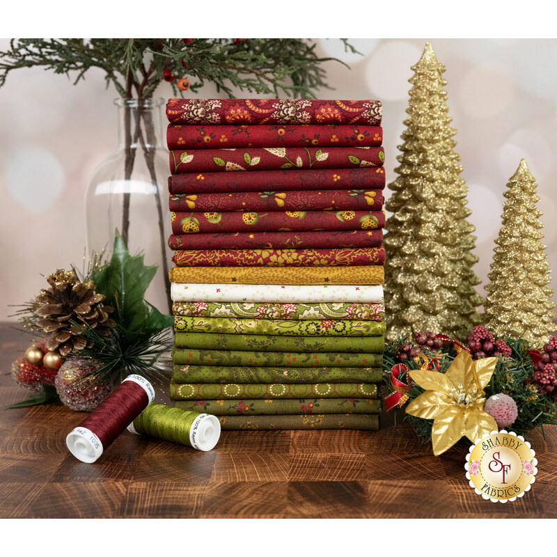 A stack of fabrics included in the Baubles & Balsam fq set, with golden trees and plants and berries and thread.
