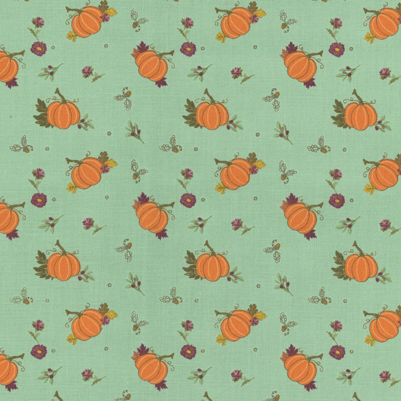Fabric with orange pumpkins and small flowers on a soft teal background.