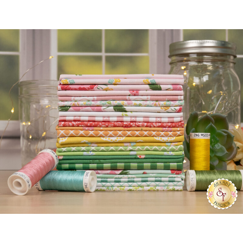 A stack of the fabrics included in the Summer Skies and Fireflies collection, with fairy lights and jars and flowers and thread.
