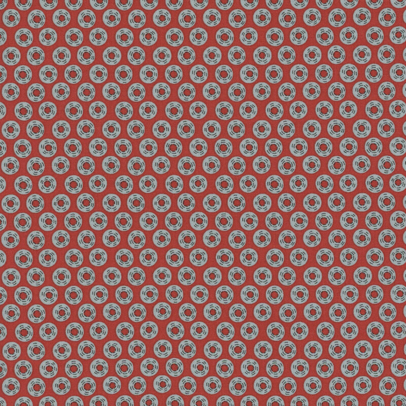 Red fabric with a repeating pattern of blue circles and red center, creating a playful design.