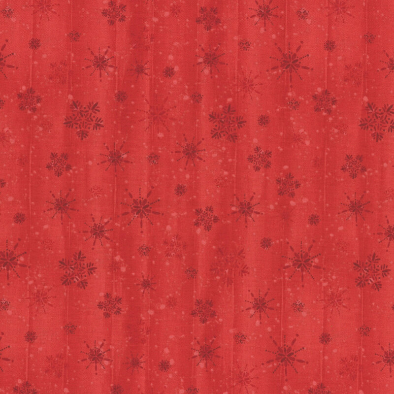 Tonal red fabric with a red background and scattered snowflakes and a wood grain textured background.