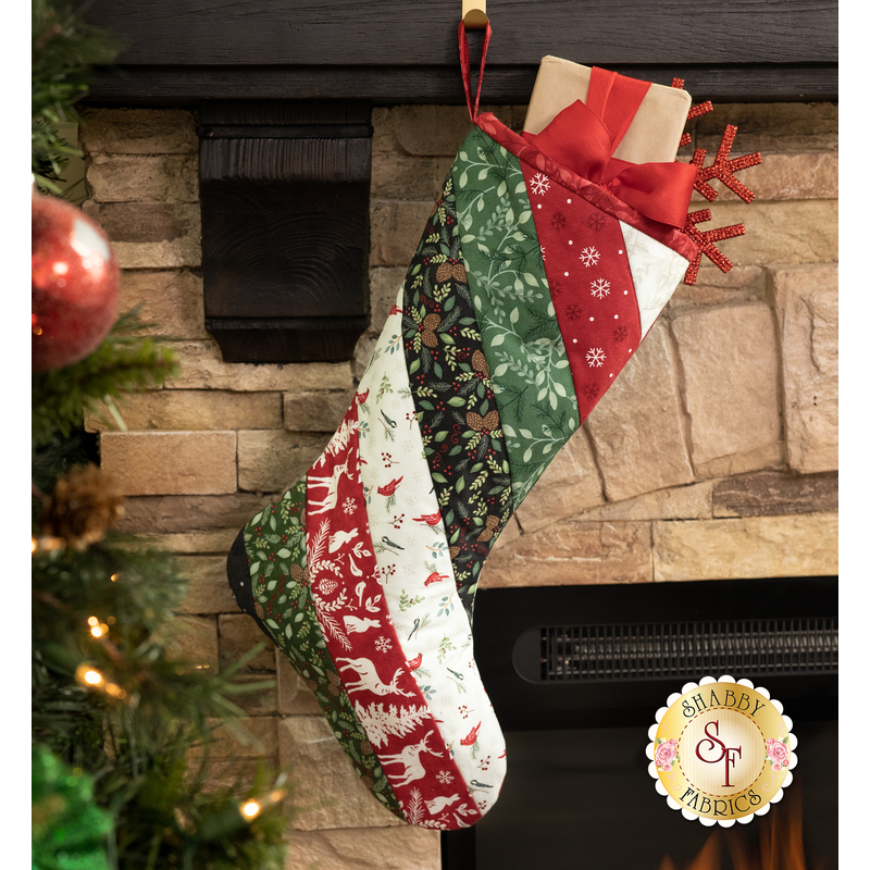 A festive Christmas stocking hanging from a stone fireplace, decorated in fabrics from the Woodland Winter collection