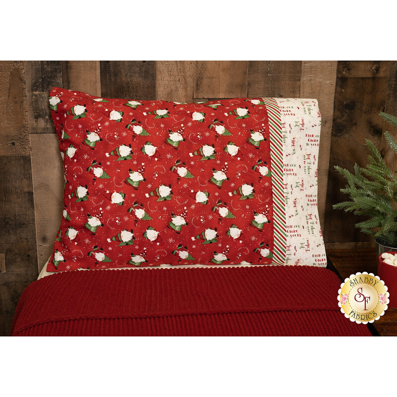 The completed Our Gnome to Yours - Standard Size Pillowcase in red, staged on a red bed against a rustic wood wall.