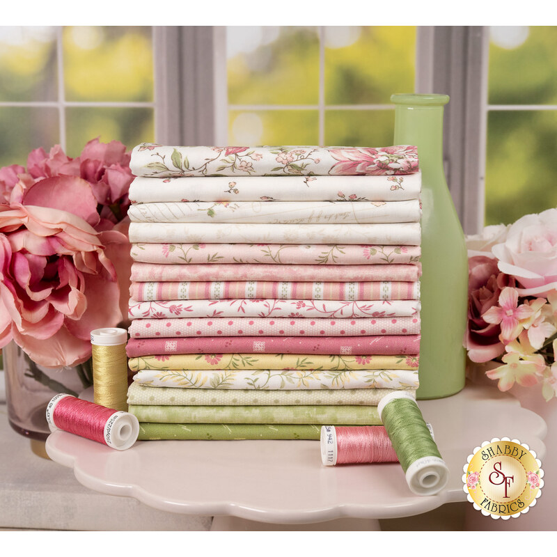 A stack of the fabrics included in the Shades of Romance collection, with flowers and a bottle and thread.