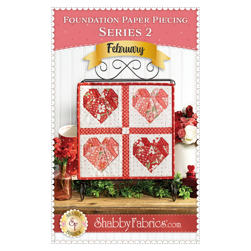 Front cover of the pattern showing the completed project in red, pink, and white fabrics, staged on a craft stand atop a rustic wood table top with coordinating holiday decor.