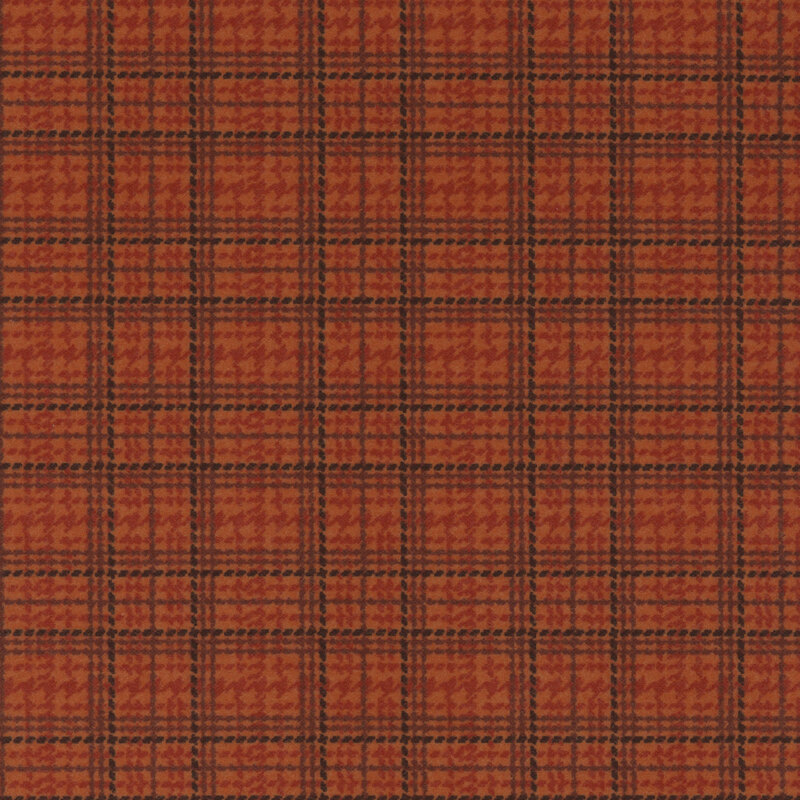 Close-up of a red and orange plaid fabric pattern with dark grid lines.