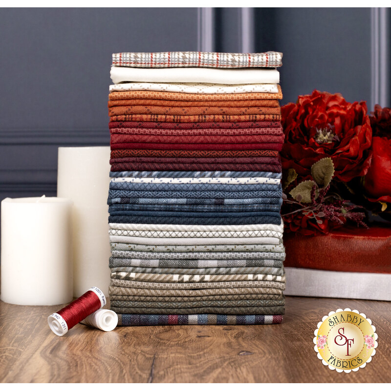 A stack of fabrics in the Prairie Gatherings Flannels Fat Eighth Set featuring various colors and patterns, with flowers, books, candles, and thread.