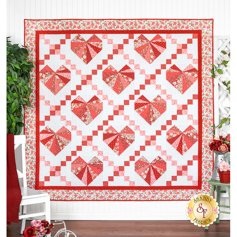 A quilt featuring large red, white and pink valentine hearts arranged in an Irish chain grid against a white background with floral borders.