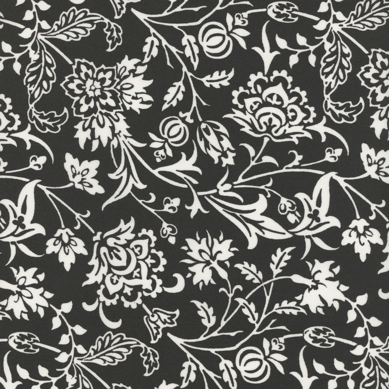 Black fabric featuring intricate white floral and vine patterns.
