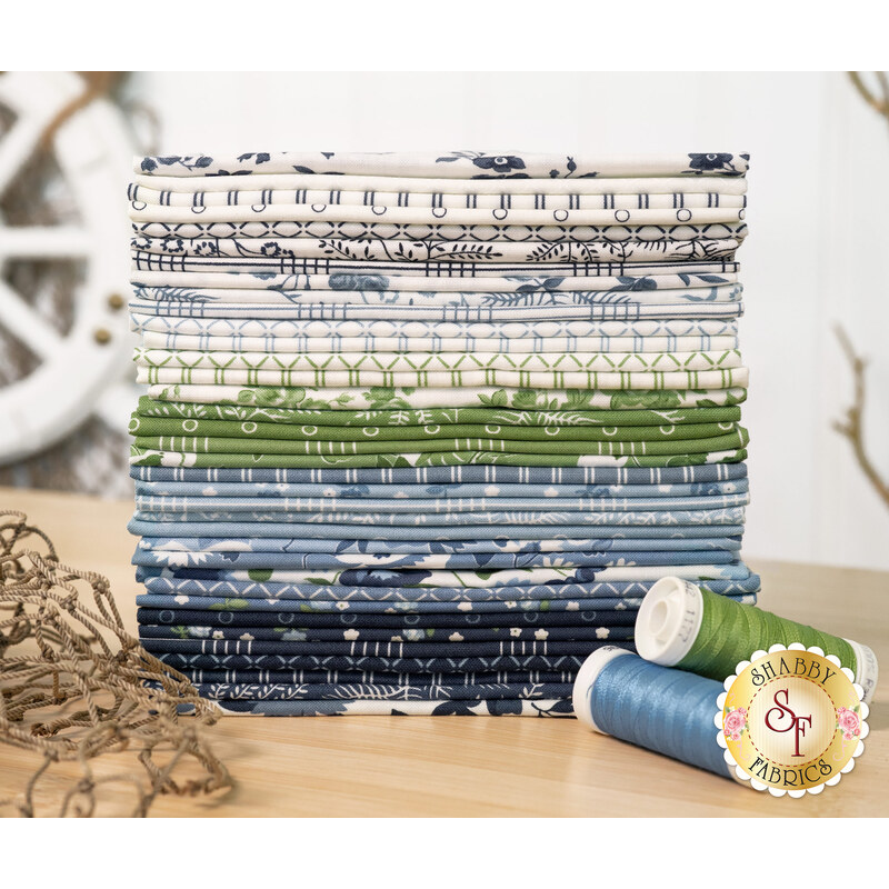 A sA stcak of fabrics included in the Nantucket Summer fabric collection by Moda Fabrics with thread, nets, a tree, and a ship wheel decoration.