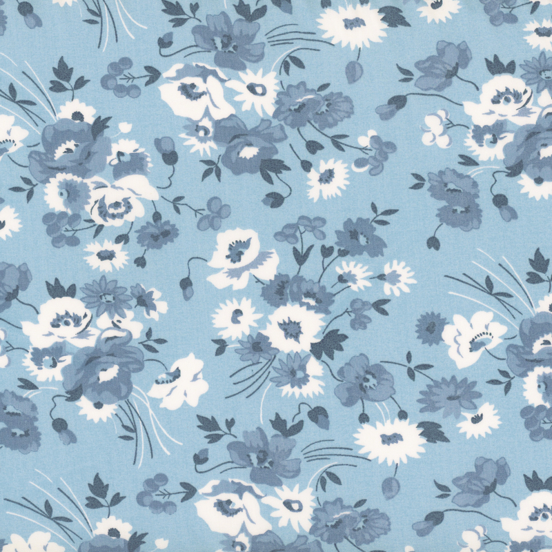 Fabric featuring various white and blue flowers on a blue background.