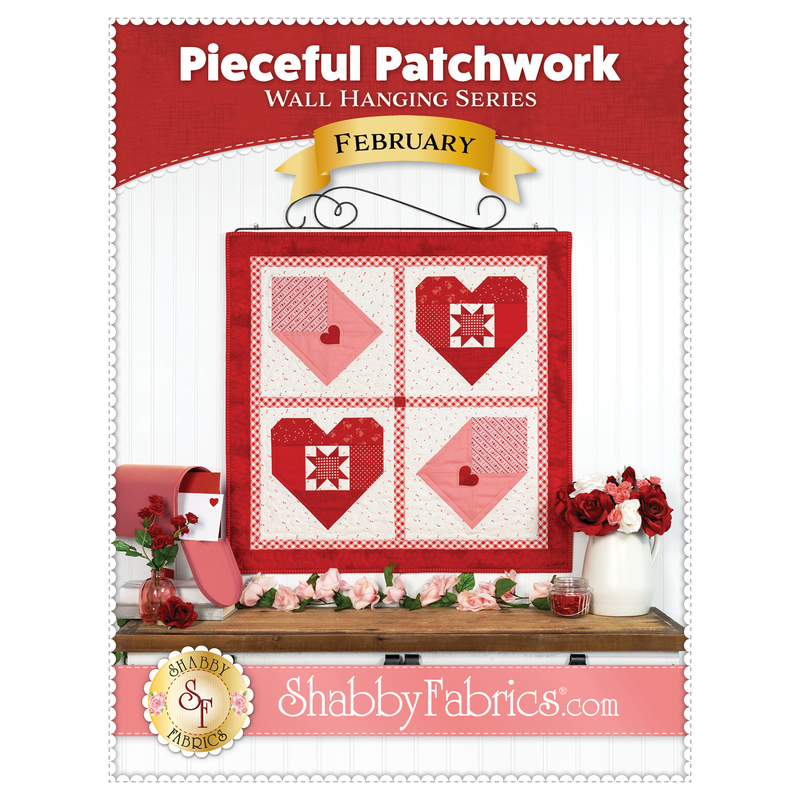 Front cover of the Pieceful Patchwork pattern for February, showing the completed wall hanging colored in red, white, and pink fabrics that make up two patchwork hearts and letters.