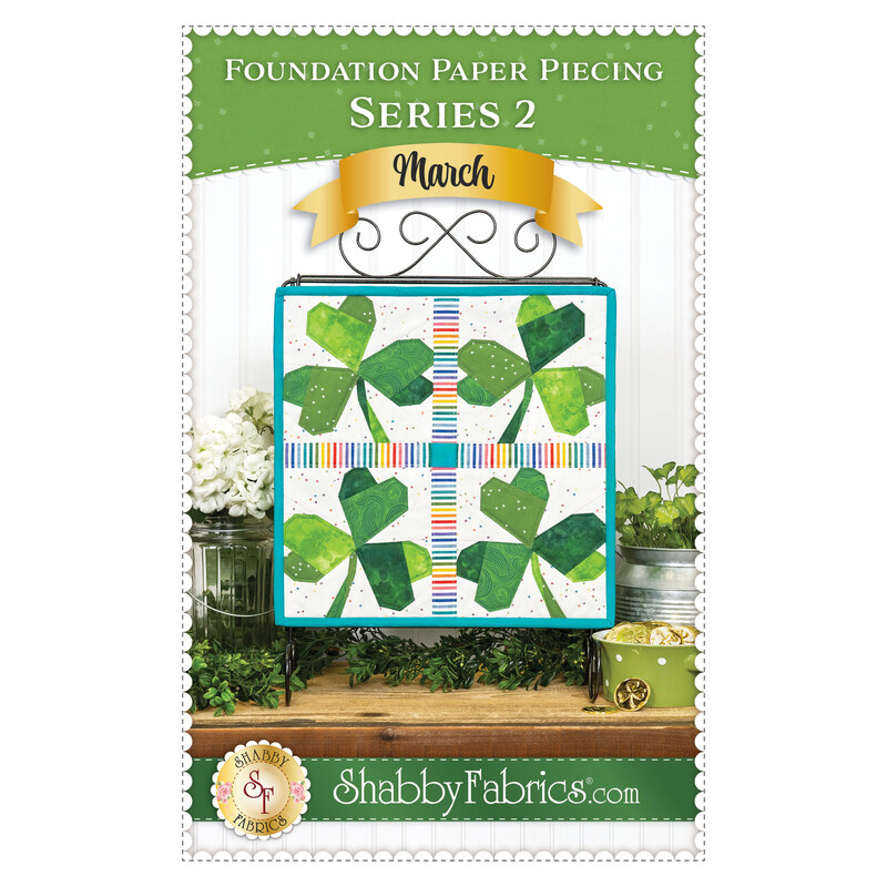 Front cover of the pattern showing the completed project in rainbow, green and white fabrics, staged on a craft stand atop a rustic wood table top with coordinating holiday decor.