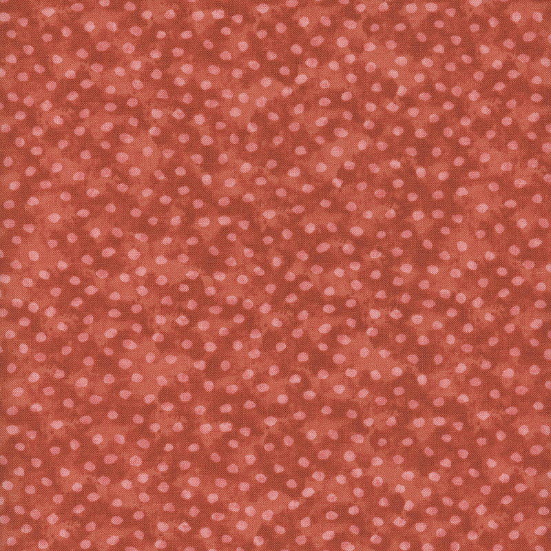 Fabirc of rust-colored fabric with small, light pink dots scattered throughout.