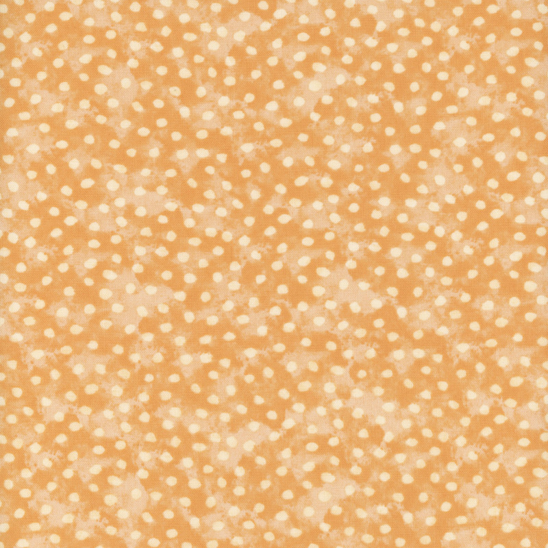 A fabric with a warm beige color and scattered white polka dots.