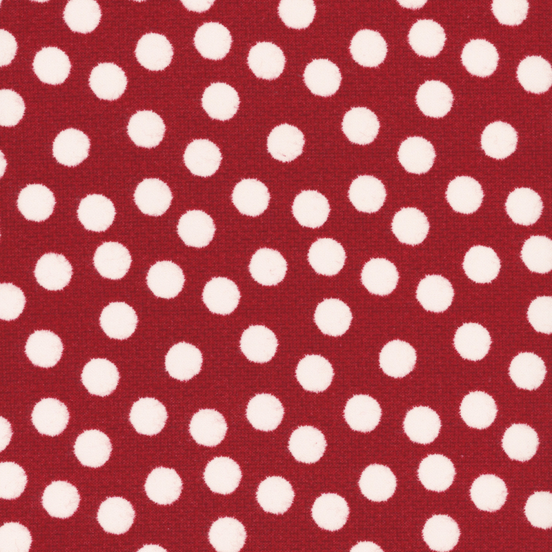 Red textured fabric scattered with white fuzzy polka dots. 