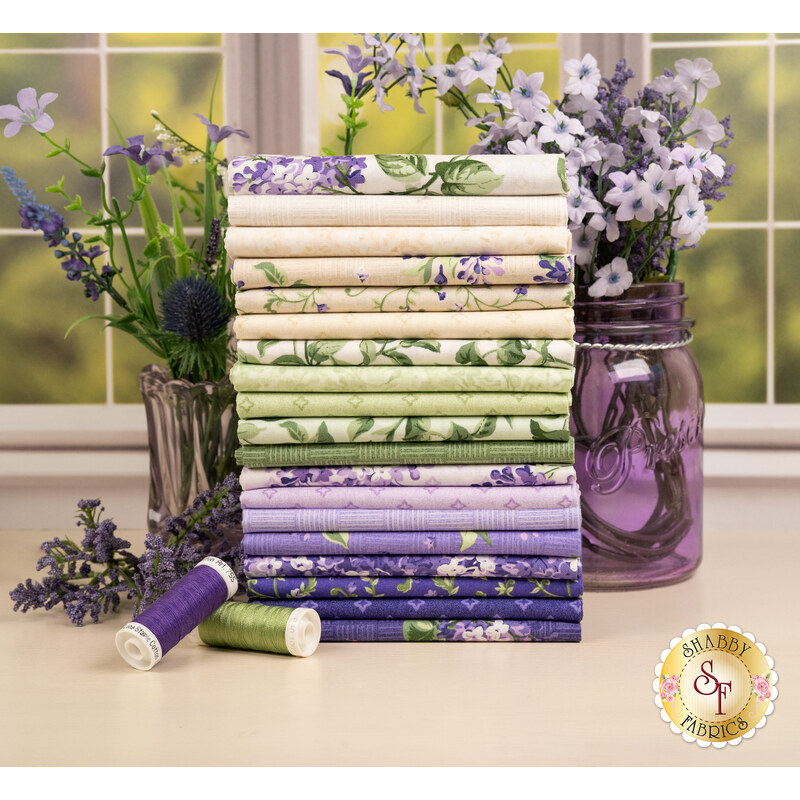 A stack of the fabrics included in the Lilac Lane collection, with flowers and jars and thread.