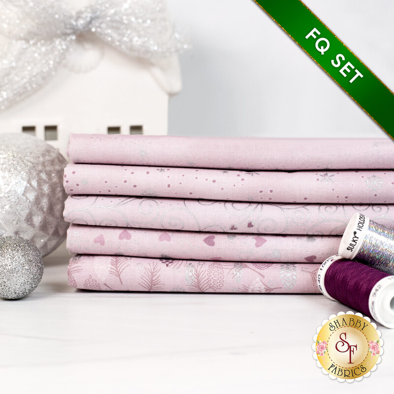 Stack of fabrics in the collection on a white surface with maroon and silver threads and a decorative ornament..