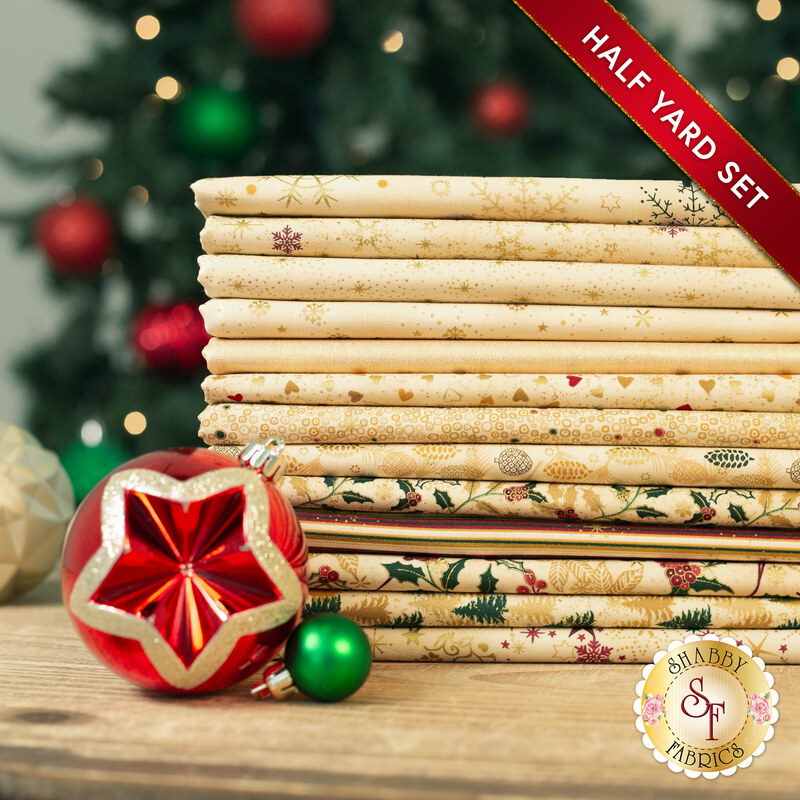 A stack of the thirteen fabrics included in the 13 Half Yard Set Tan/Gold by Stof Fabrics, with christmas trees and ornaments.