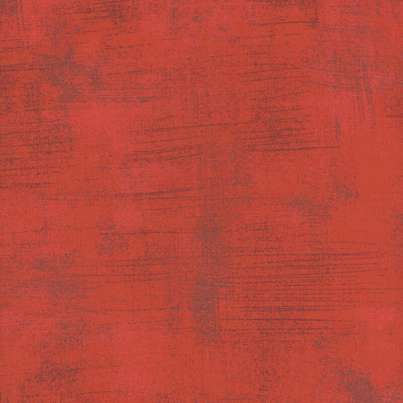 Textured abstract fabric in shades of red with subtle variations and scratches.