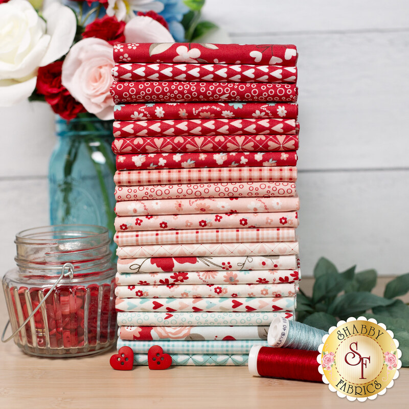 A stack of the fabrics included in You & Me by Riley Blake Designs, with flowers and thread and buttons.