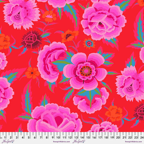 Vibrant red fabric with large pink and purple floral patterns and green leaves, bordered by a measuring scale.