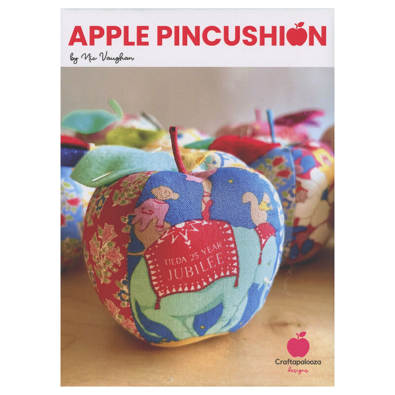 The front of the Apple Pincushion pattern, featuring the finished pincushion displayed with others on a wooden table.