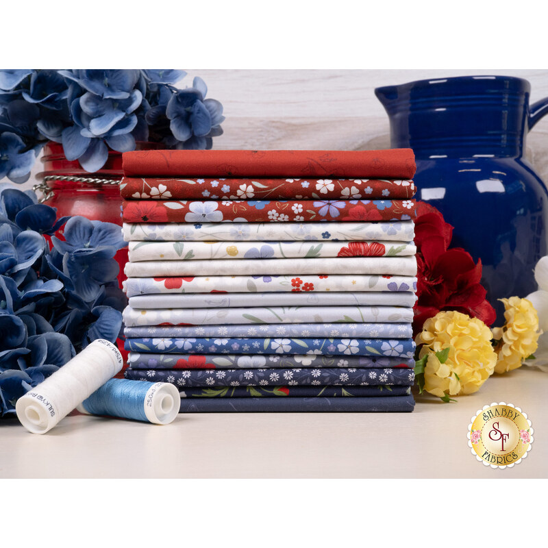 A fabric stack of the fabrics included in the Forever Blooms FQ collection, with flowers and a pitcher and thread.