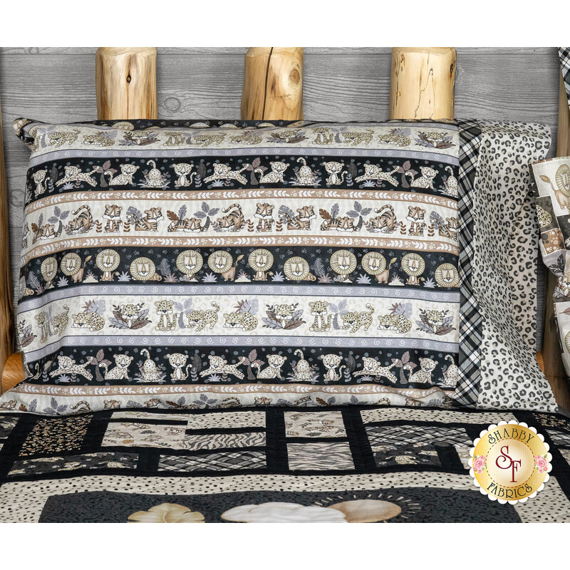 A pillow with patterned fabric featuring animal prints and a coordinated quilt in a rustic setting.