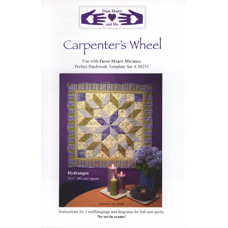 The front of the Carpenter's Wheel pattern with the finished quilt hung on a purple wall with a decorated table in front.