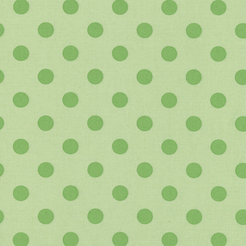 Light green fabric with evenly spaced, varying-sized dark green polka dots.