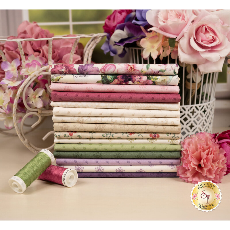 A stack of the fabrics included in the Cottage Lace FQ set with flowers and backets and thread.