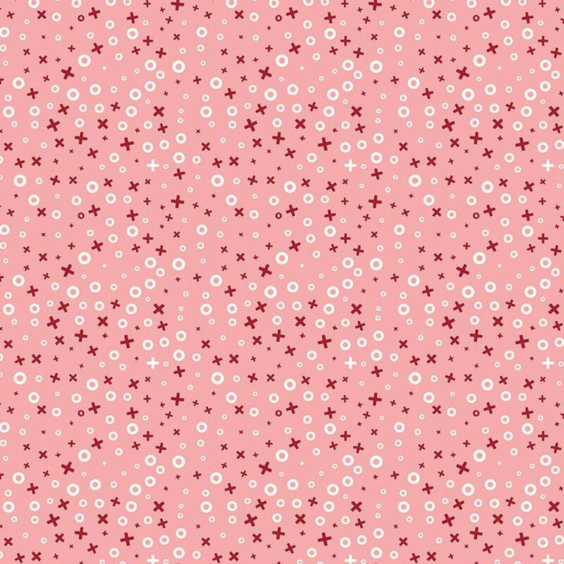 A pink fabric featuring a pattern of small red crosses and white circles scattered throughout.