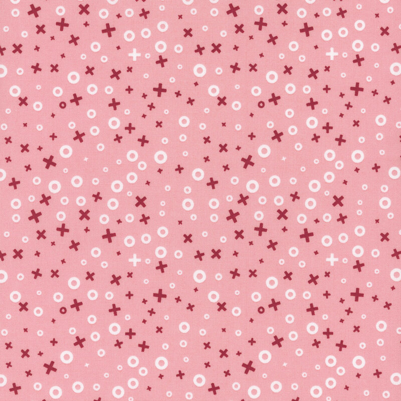 A pink fabric featuring a pattern of small red crosses and white circles scattered throughout.