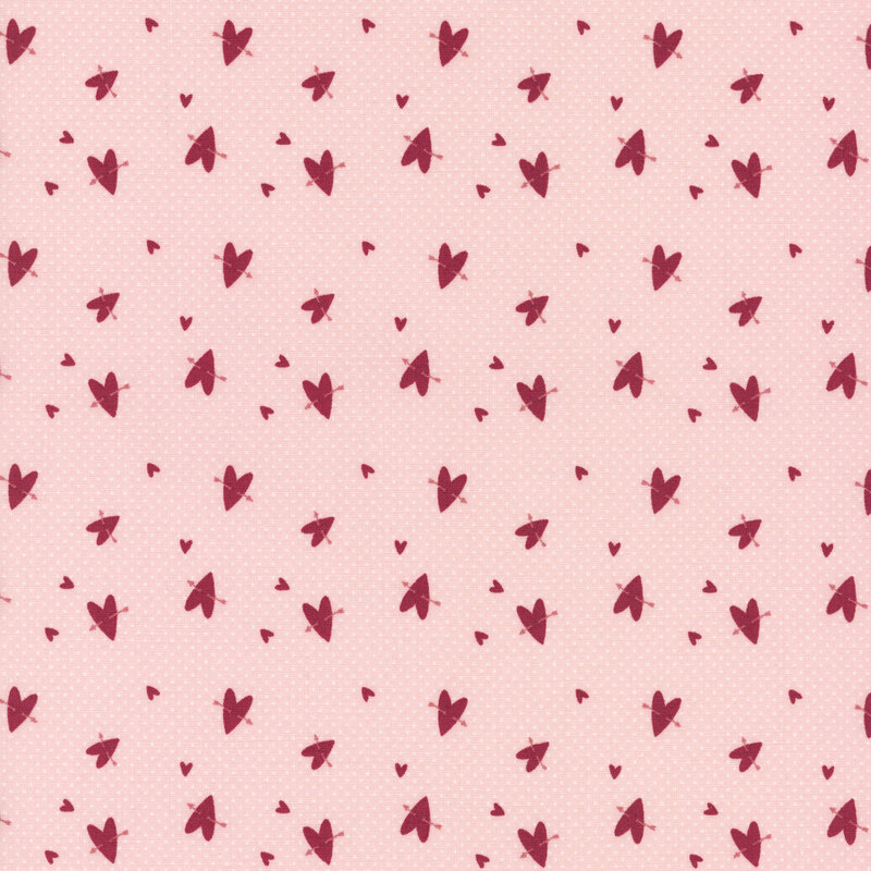 A light pink fabric with a scattered pattern of small red hearts.