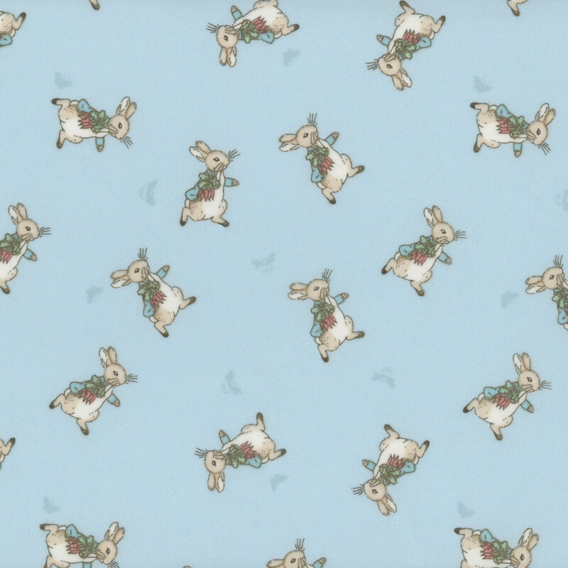 fabric pattern of peter rabbit in alternating poses over a baby blue background